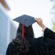 Photo shows the back of a woman's head. She has long dark hair and is wearing a graduation cap.