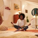 woman sits in the middle of her room calmly on the floor