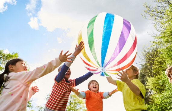 A group of children happily playing with a large beach ball.
