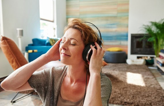 A woman smiles while listening to music on her headphones.
