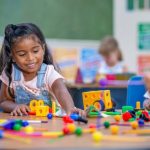 A young girl reaches out to play with scientific building blocks.